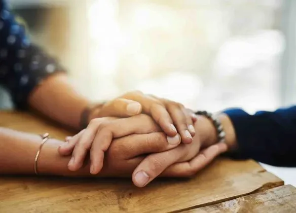 Gros plan sur deux paires de mains serrées en signe de réconfort et de soutien.